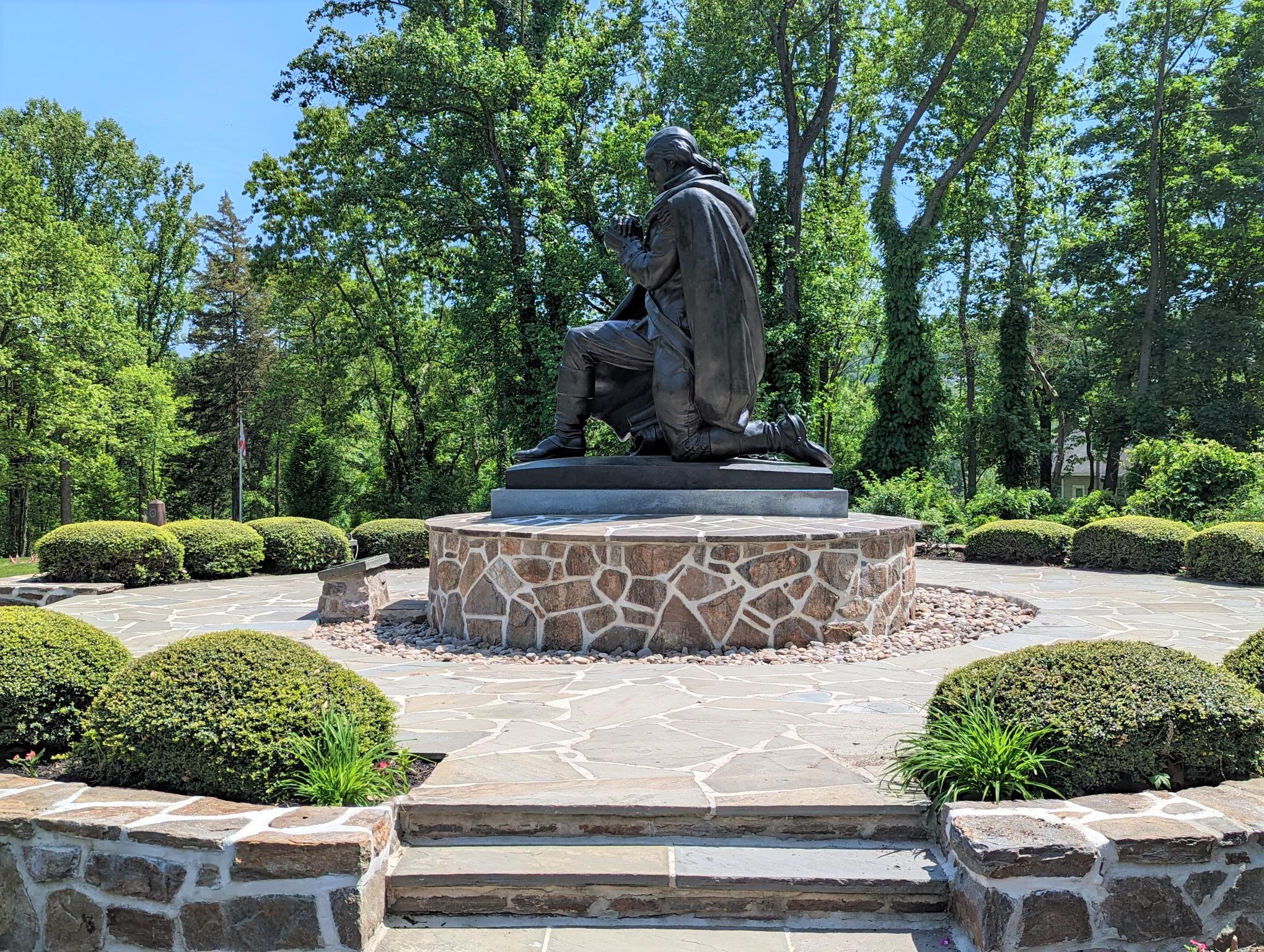 Side view of statue depicting George Washington at prayer with gardens surrounding the statue.