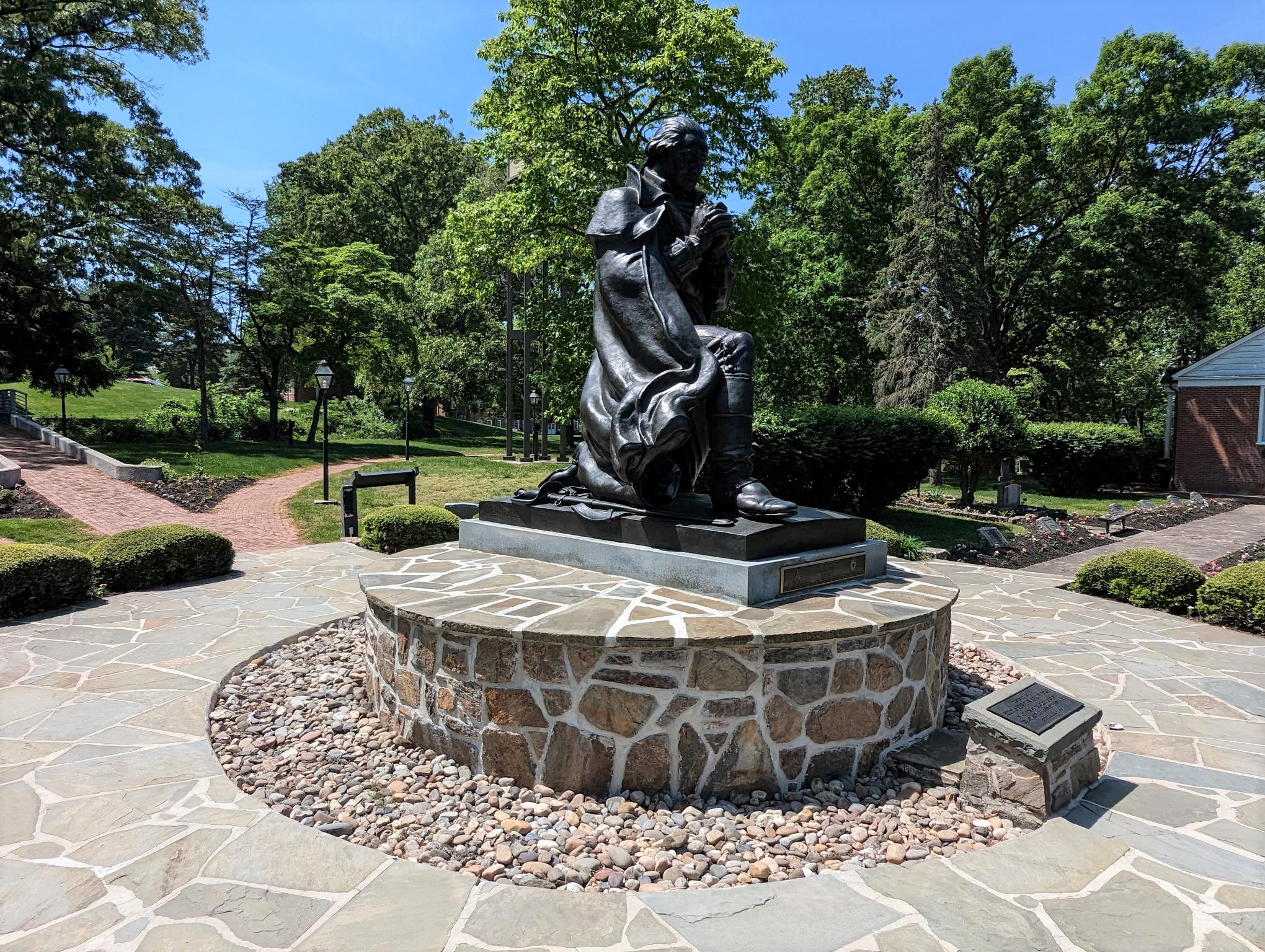 Side view of statue depicting George Washington at prayer with gardens surrounding the statue.