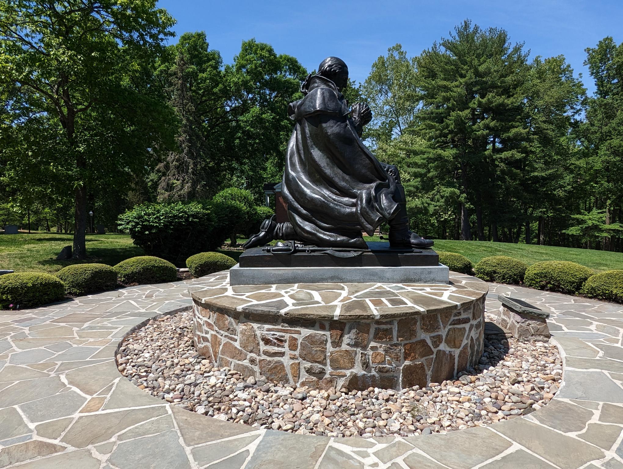 Side view of statue depicting George Washington at prayer with gardens surrounding the statue.