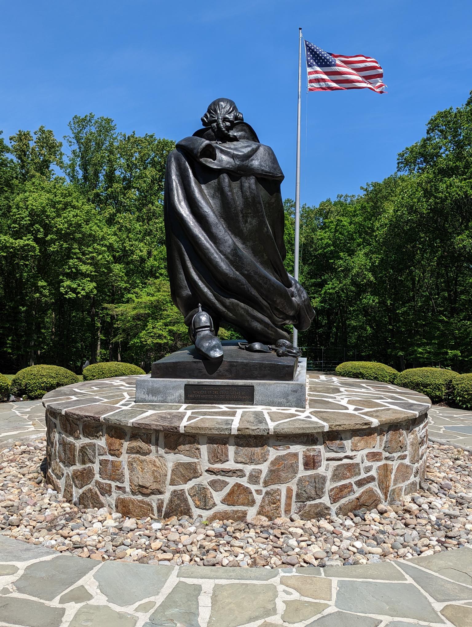 Back view of statue depicting George Washington at prayer with gardens surrounding the statue.